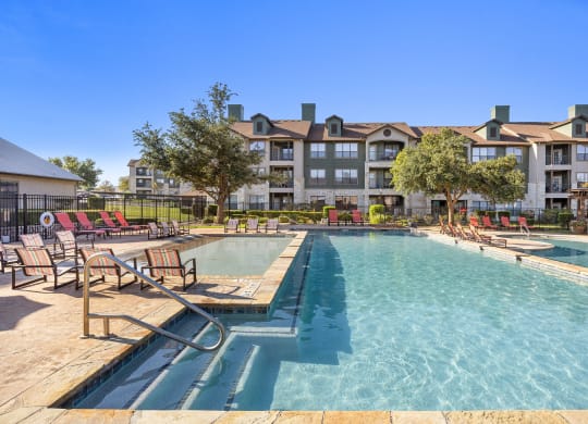 pool with chairs and apartment buildings at The Fairways at Star Ranch, Hutto, Texas