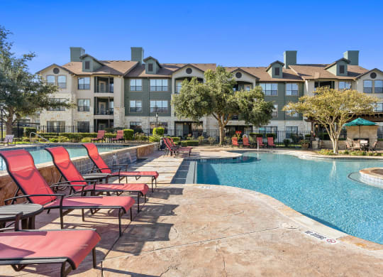commons pool with chairs and an apartment building at The Fairways at Star Ranch, Hutto