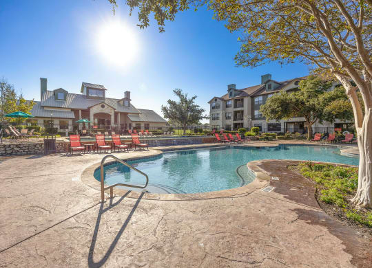 a resort style pool with chairs and a building in the background at The Fairways at Star Ranch, Hutto, TX, 78634
