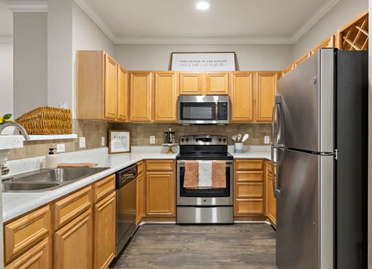 a kitchen with wooden cabinets and stainless steel appliances at The Verandah, Austin, TX