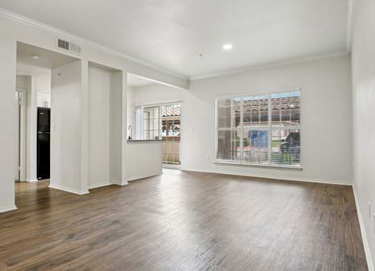 A spacious room with wooden floors and white walls.