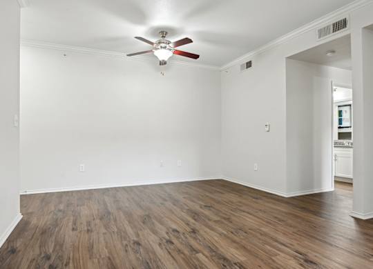 A room with a ceiling fan and wooden flooring.