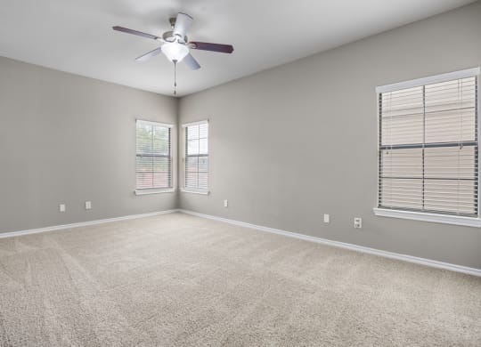 An empty room with a ceiling fan and two windows at Waters Edge Apartment Homes, Georgetown, 78626