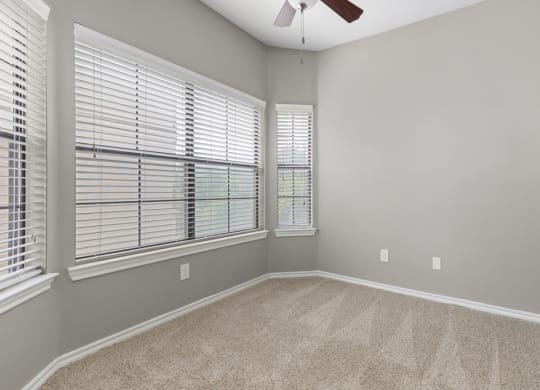 A bedroom with two large windows and a ceiling fan at Waters Edge Apartment Homes, Georgetown, TX