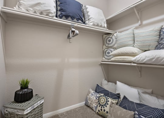 a walk in closet in a bedroom with pillows on the floor and a shelf with pill at Artisan Apartments & Shops, Austin, Texas