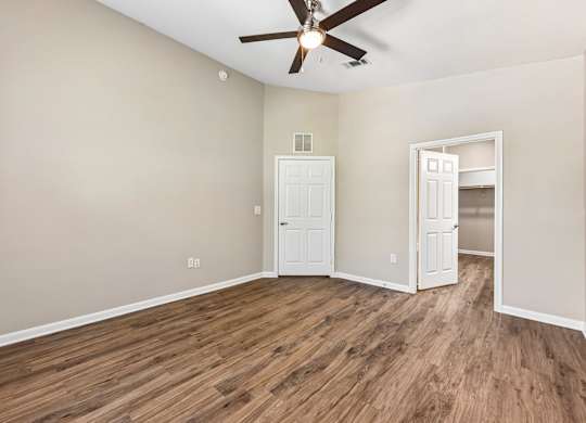 A room with a ceiling fan and wooden flooring.