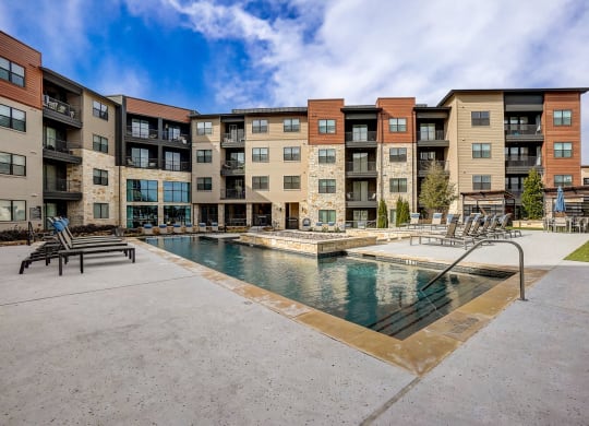 a swimming pool with an apartment building in the background at Aurora Watson Branch, Mansfield, TX, 76063