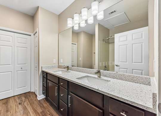 A bathroom with a white door, brown cabinets, and a marble countertop.