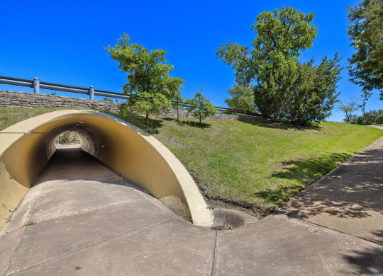 a tunnel on the side of a hill with grass and trees at Lakeline East Apartments, Cedar Park, TX