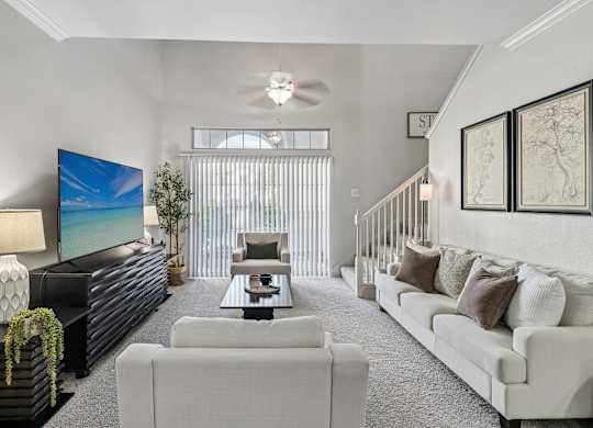 A living room with a white couch, a black coffee table, and a large painting on the wall.