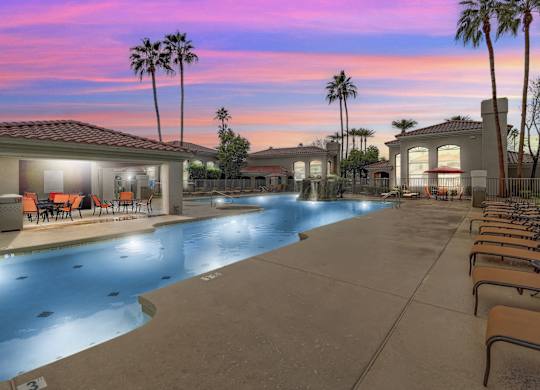 A swimming pool with lounge chairs and palm trees at San Montego Apartments, Arizona