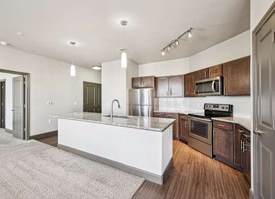 A modern kitchen with a white island and wooden cabinets.at North Creek, Texas, 78634