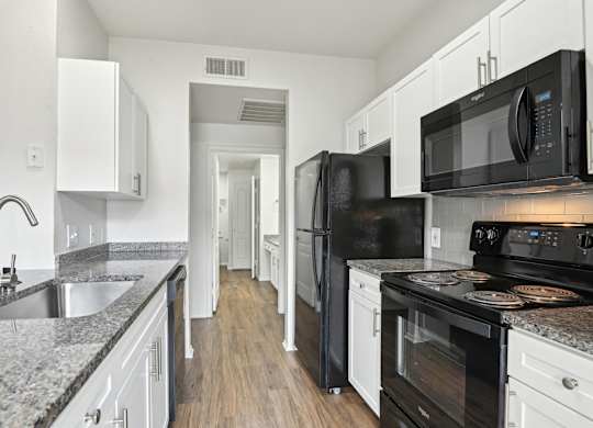 A kitchen with black appliances and white cabinets.