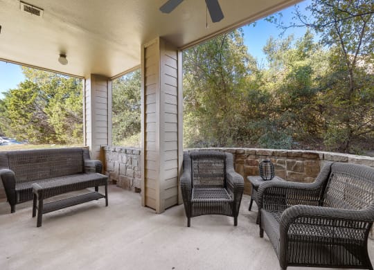 a covered patio with wicker furniture and a large window at The Verandah, Austin, TX
