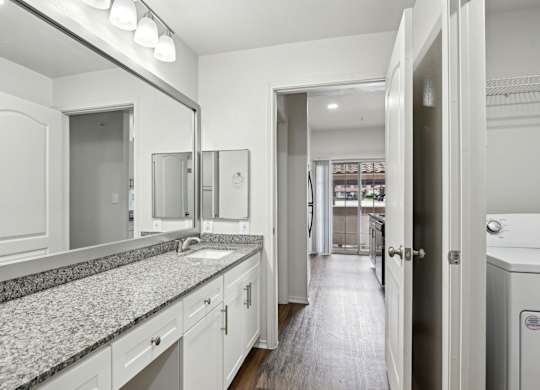 A bathroom with a granite countertop and white cabinets.