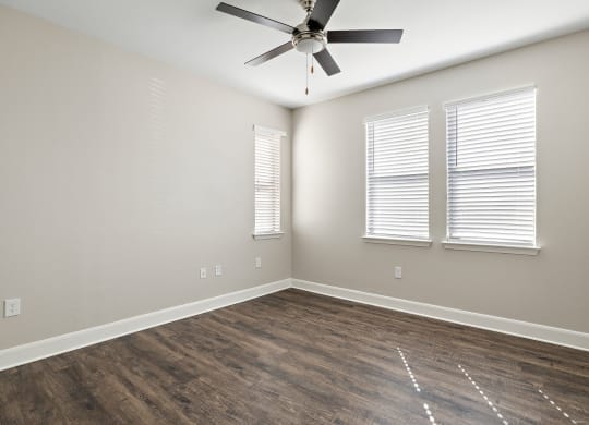 an empty living room with wood floors and a ceiling fan at The Verandah, Austin, TX