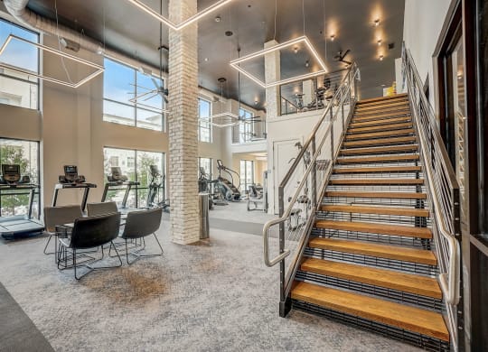 the landing of the staircase in the lobby of a building with a gym and chairs at Aurora Watson Branch, Texas