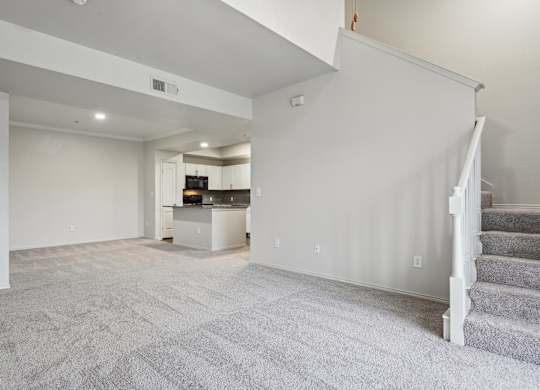 A spacious living room with a staircase on the right side.