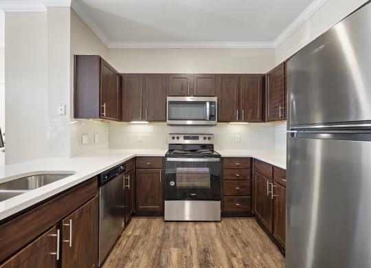 a kitchen with stainless steel appliances and wooden cabinets at The Verandah, Austin, TX, 78726