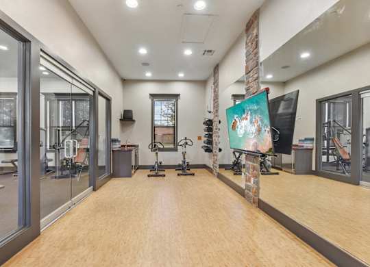 A gym with wooden floors and various exercise equipment.