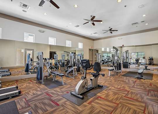 A gym with a variety of equipment including treadmills, weights, and exercise machines.
