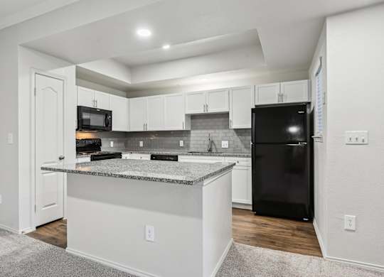 A kitchen with a black refrigerator and white cabinets.