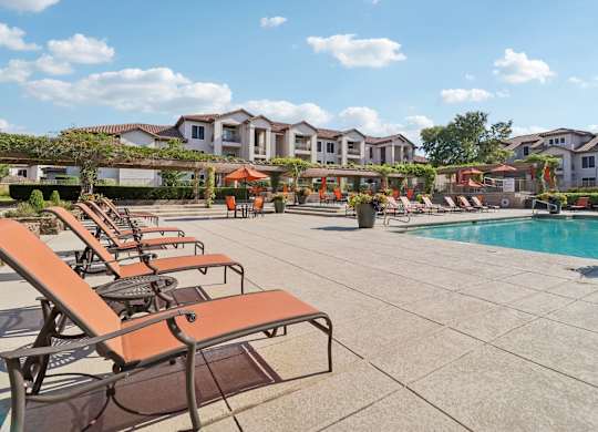 A pool area with sun loungers and a swimming pool.