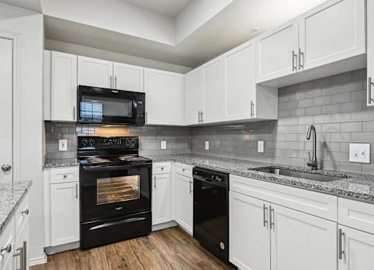A kitchen with black appliances and white cabinets.