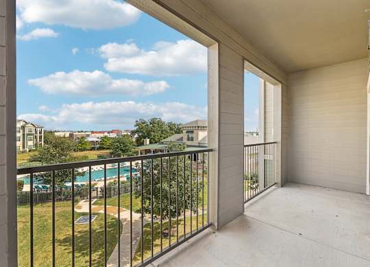 A balcony with a black railing and a pool in the distance. at North Creek, Hutto