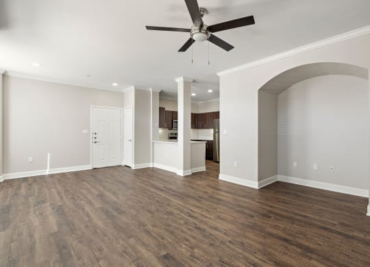 an empty living room with a ceiling fan and a kitchen at The Verandah, Austin, 78726