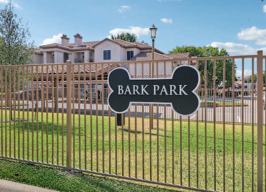 A sign that says Bark Park is on a fence.