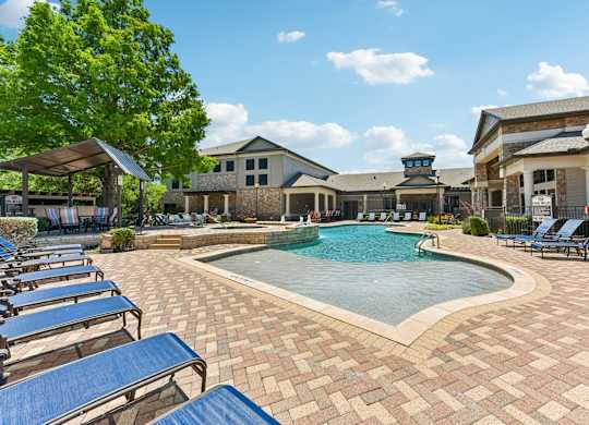 A pool surrounded by blue lounge chairs and a building in the background.