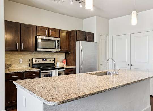 A kitchen with a granite countertop and white cabinets.at North Creek, Hutto, TX