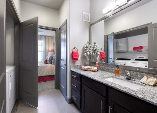 a bathroom with a sink and a mirror and a door to a bedroom at North Creek, Hutto, TX