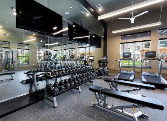 a gym with a row of weights and a large mirror at North Creek, Hutto, TX