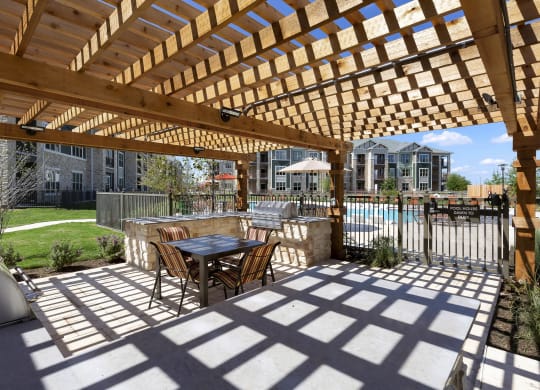 a patio with a table and chairs under a wooden pergola at North Creek, Hutto, TX