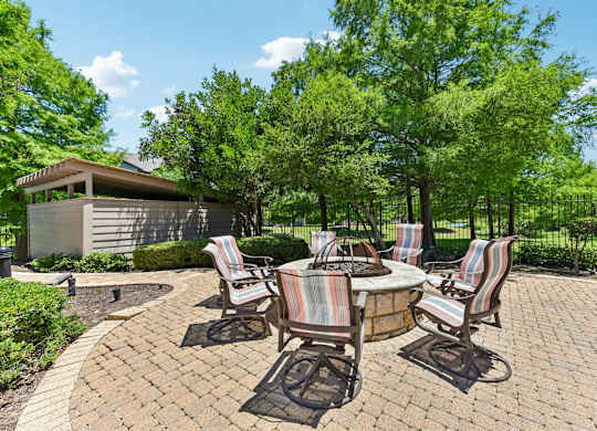 A patio with a table and chairs surrounded by trees.