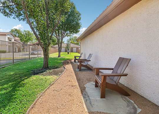 A brown wooden bench sits on a concrete slab next to a wall.