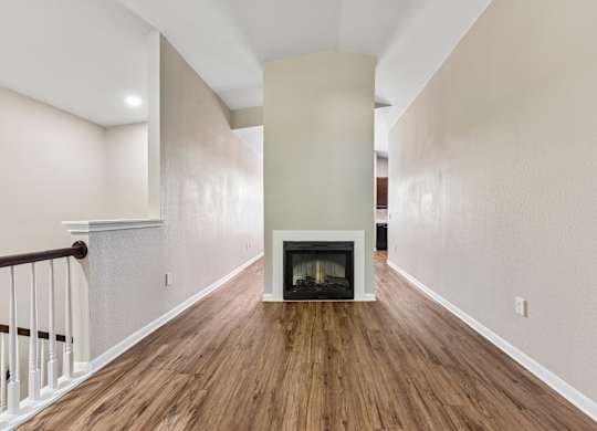 A long hallway with a fireplace and wood floors.