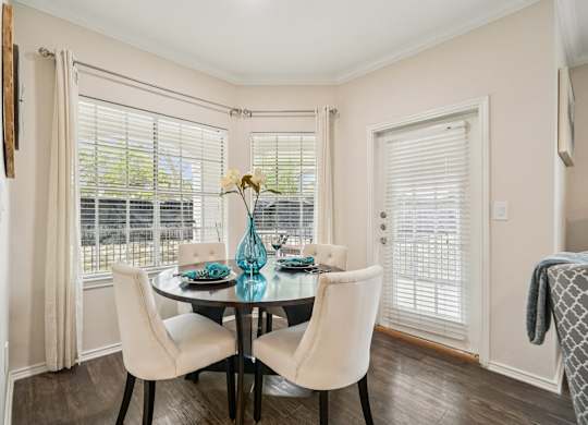 A dining room with a table set for two and a view of a balcony.