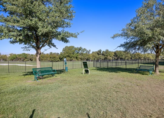 a park with benches and trees in front of a fence at The Fairways at Star Ranch, Hutto, Texas