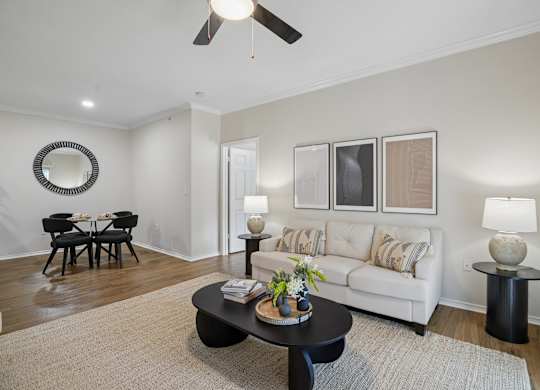 A living room with a white couch, a black coffee table, and a round mirror on the wall.