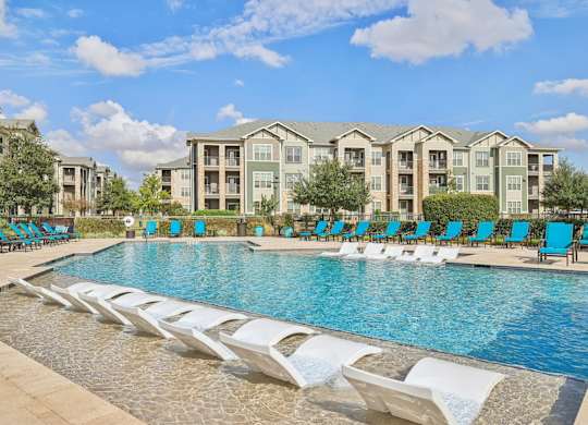 A swimming pool with lounge chairs and apartment buildings in the background.at North Creek, Texas, 78634