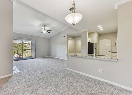A spacious living room with a ceiling fan and sliding glass doors. at Sonterra Apartment Homes, Austin, 78726