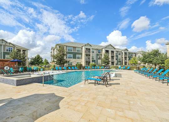 A large swimming pool surrounded by lounge chairs in front of apartment buildings.at North Creek, Hutto