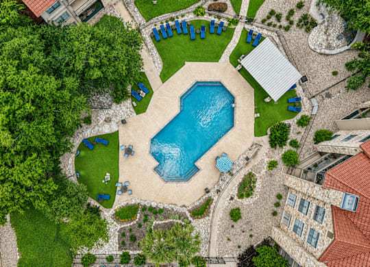 A large swimming pool surrounded by a grassy area and trees.