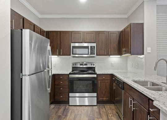 a kitchen with dark wood cabinets and stainless steel appliances at The Verandah, Austin, Texas