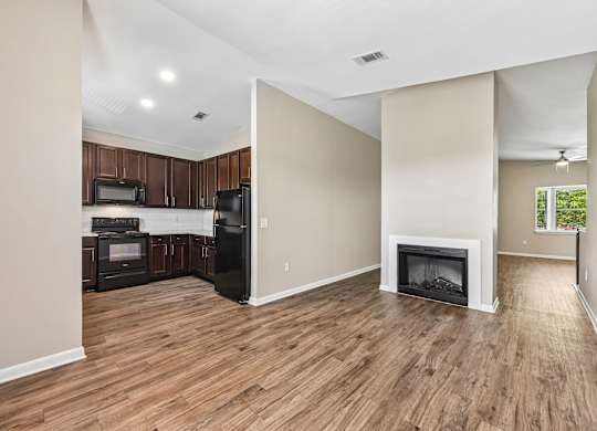 A living room with a fireplace and a kitchen area with appliances.