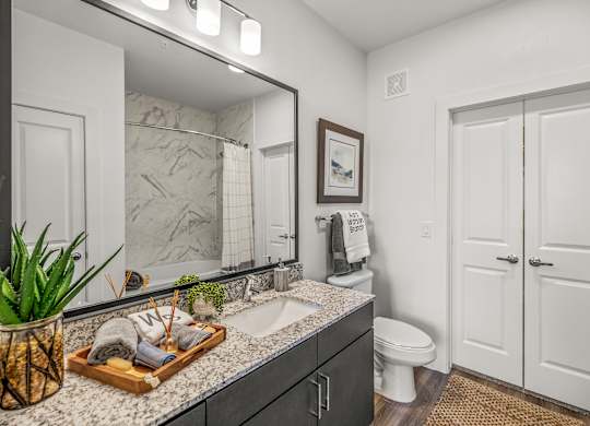 A bathroom with a marble countertop and a wooden tray with toiletries on it. at Aurora Watson Branch, Mansfield, TX
