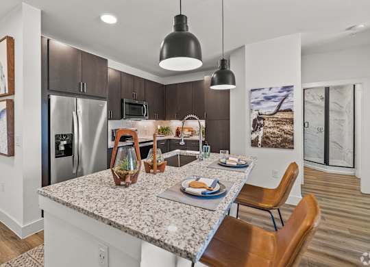 A modern kitchen with a granite countertop and stainless steel appliances.